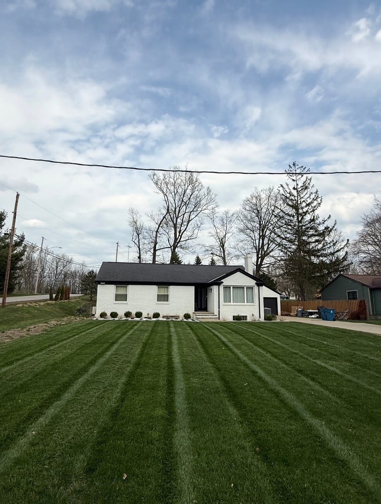 Single-story white house with freshly mowed lawn showing professional striping pattern