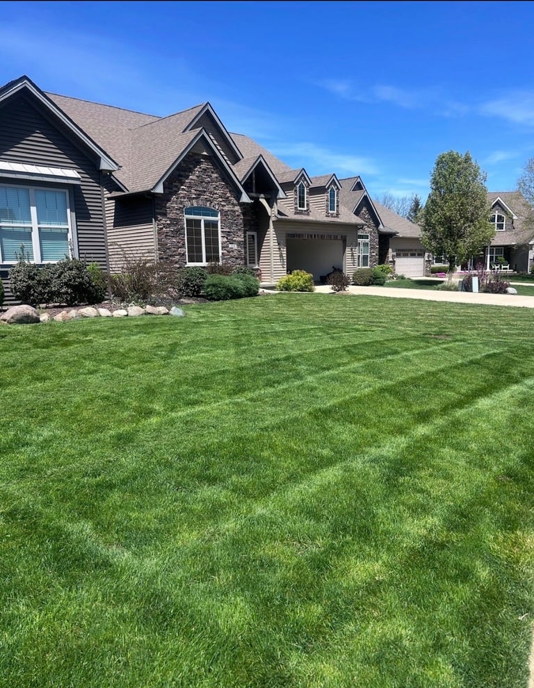 Modern two-story house with stone and siding exterior and manicured green lawn